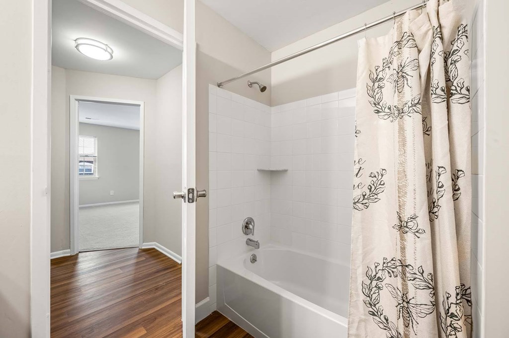 A bathroom with a shower and a wooden floor.
