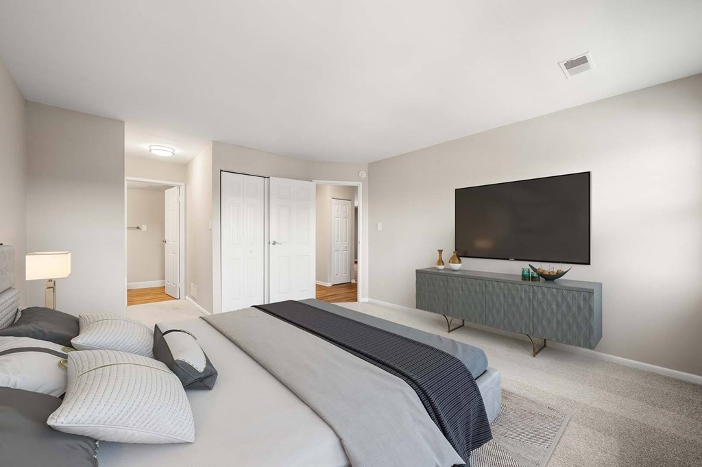 A bedroom with a large bed and a television on a cabinet.