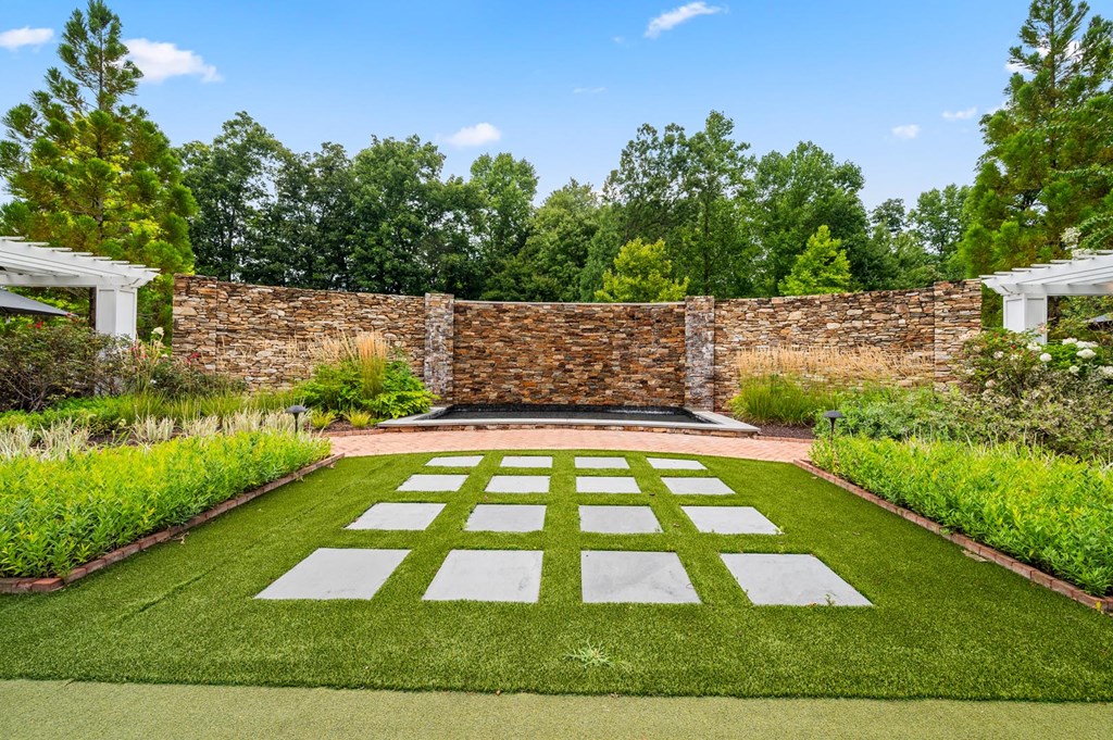 A garden with a white lawn and a stone wall.
