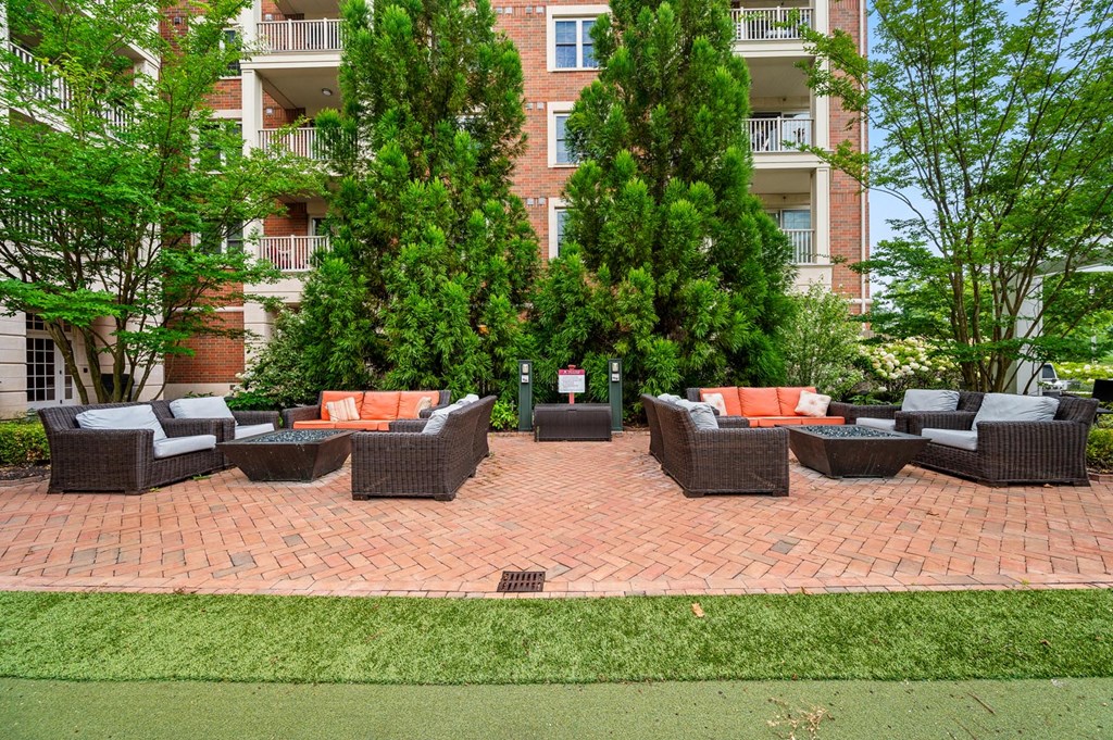 A patio with a table and chairs is surrounded by trees and apartment buildings.