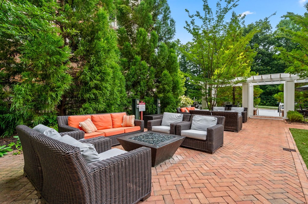 A patio with a table and chairs surrounded by greenery.