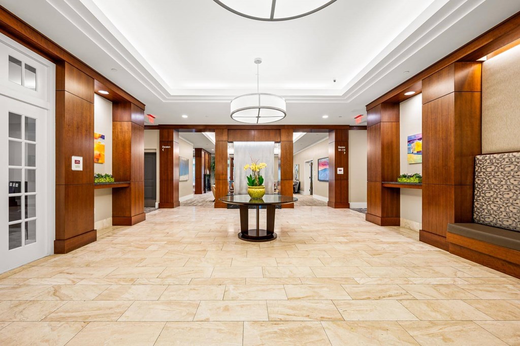 A hallway with a table in the middle and a chandelier hanging from the ceiling.