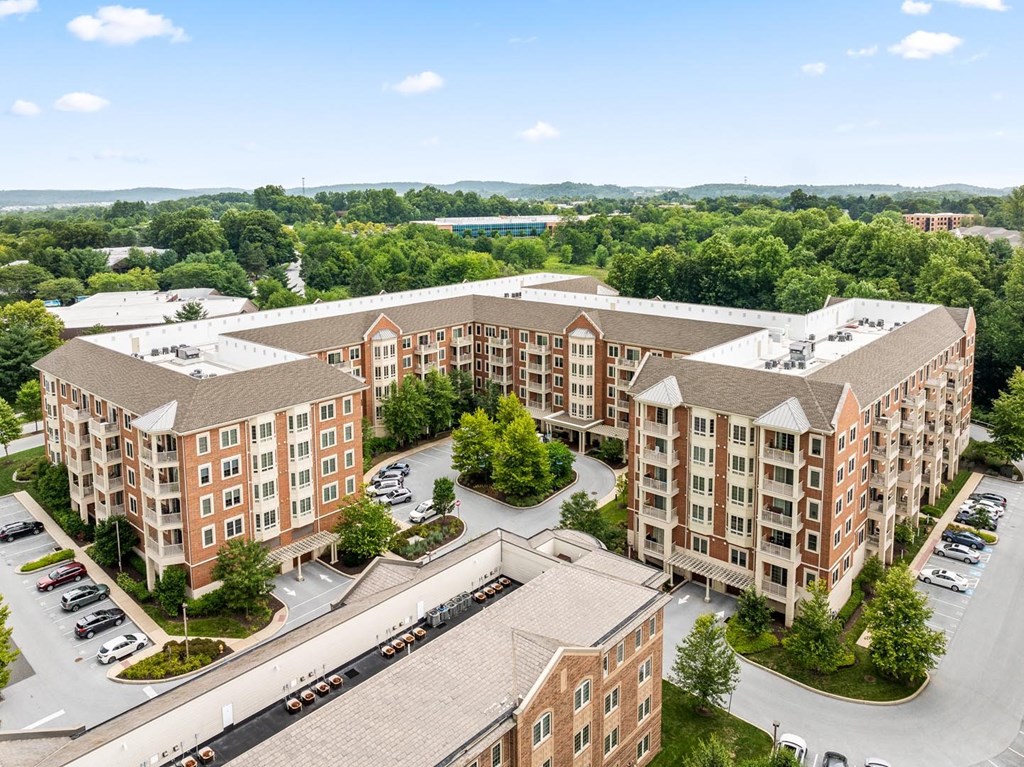 A large apartment complex with a parking lot in front.