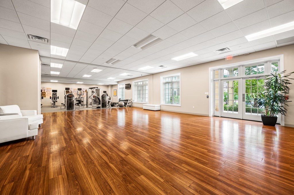 A spacious room with wooden floors and white furniture.