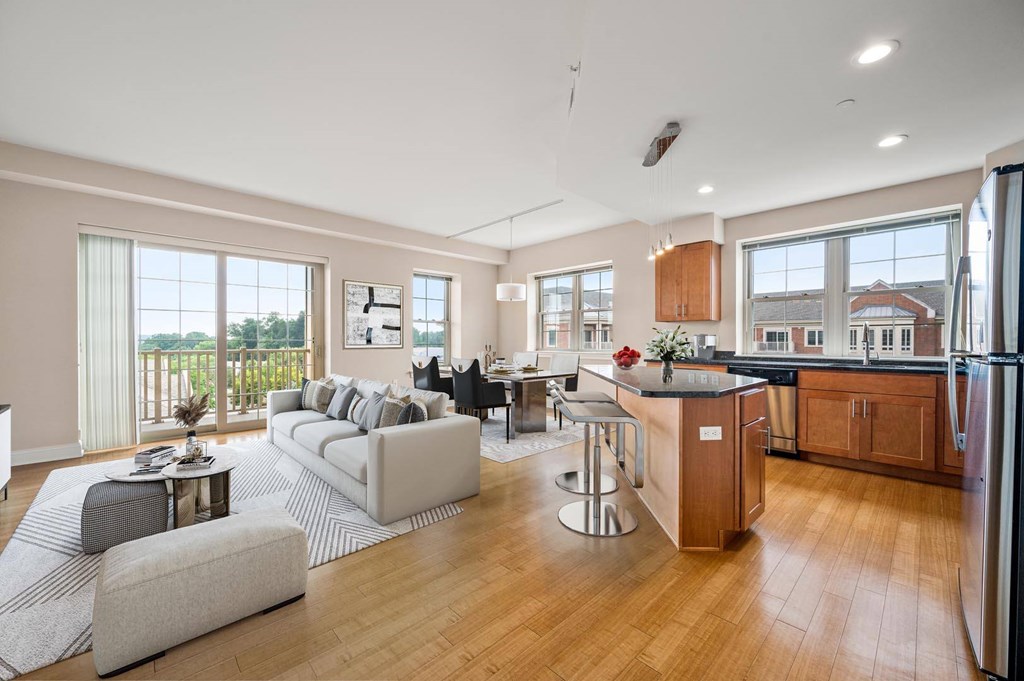 A modern kitchen with a refrigerator, sink, and wooden cabinets.