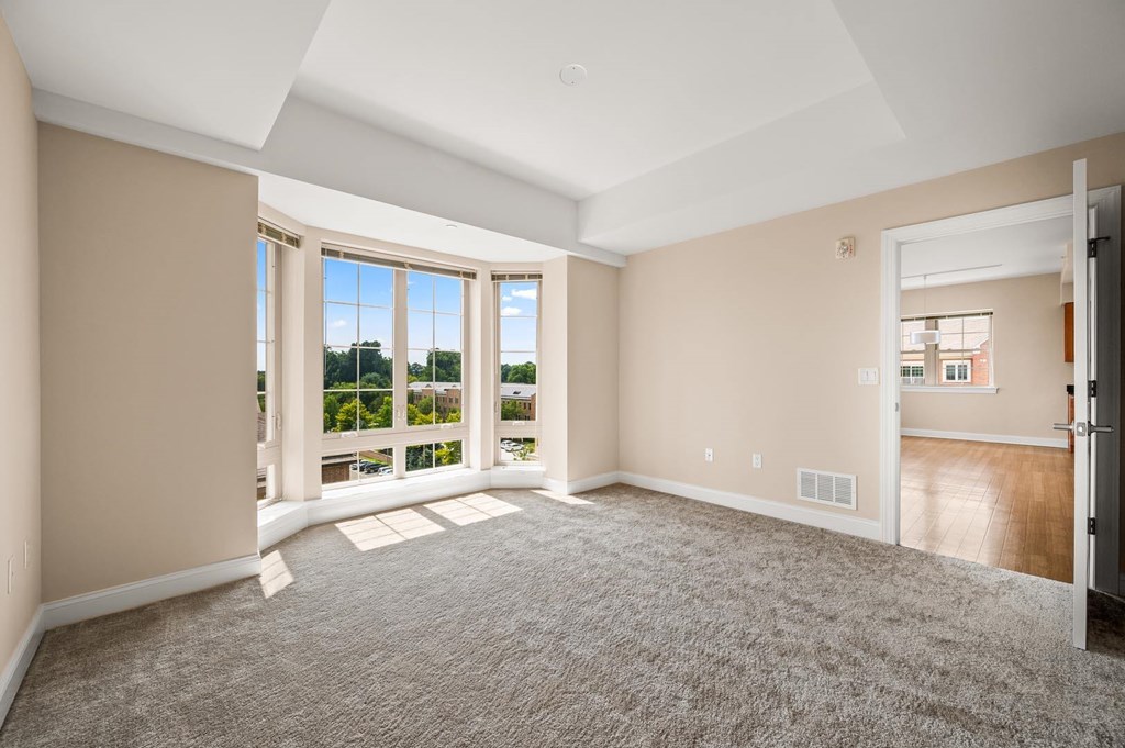 A spacious room with a carpeted floor and a view of the outside through the windows.