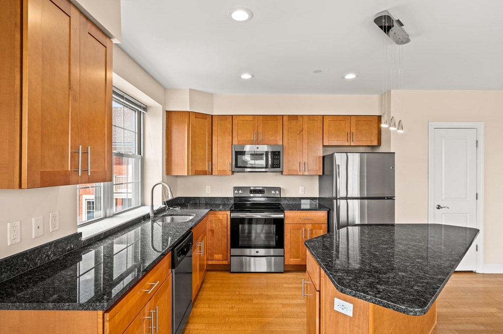 A kitchen with wooden cabinets and black countertops.
