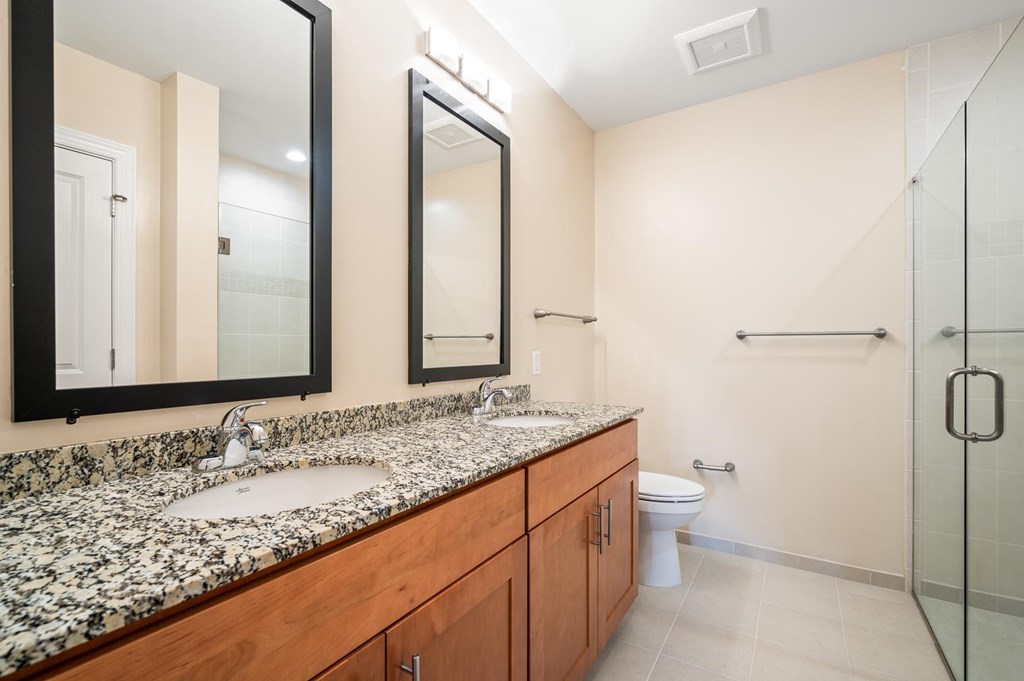 A bathroom with a marble counter top and a walk in shower.