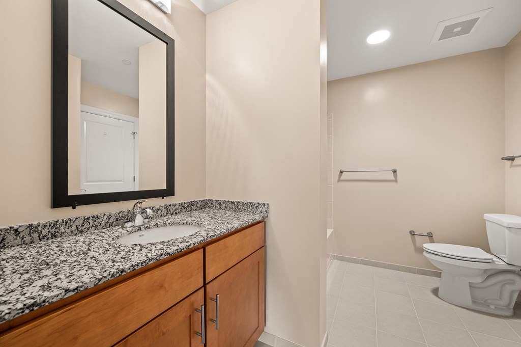 A bathroom with a sink, mirror, and toilet.