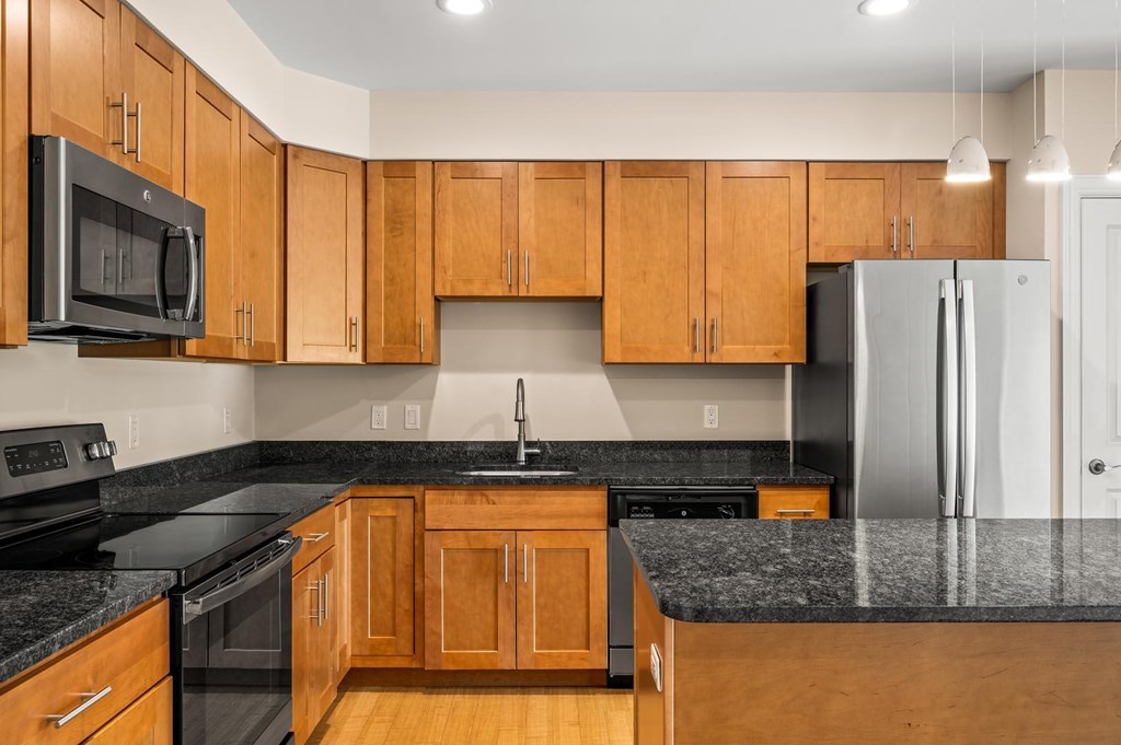 A kitchen with wooden cabinets and black countertops.