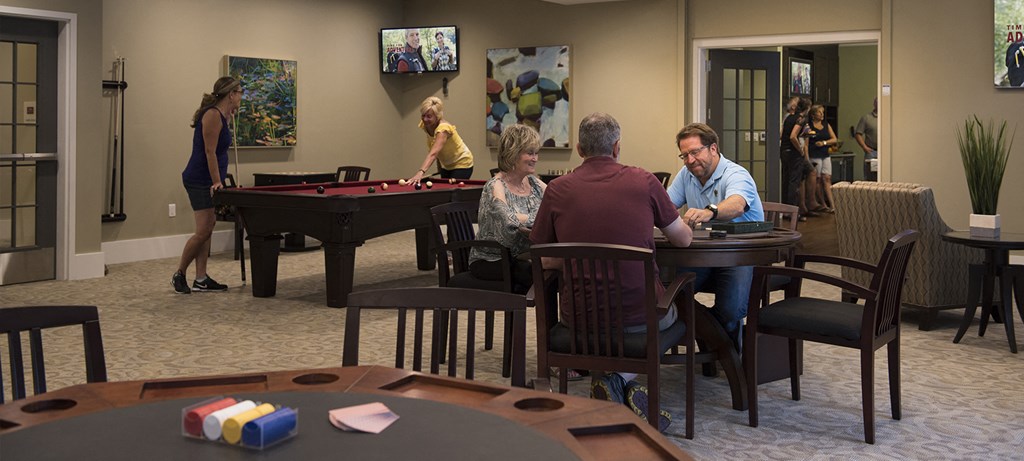 A group of people playing pool in a room.