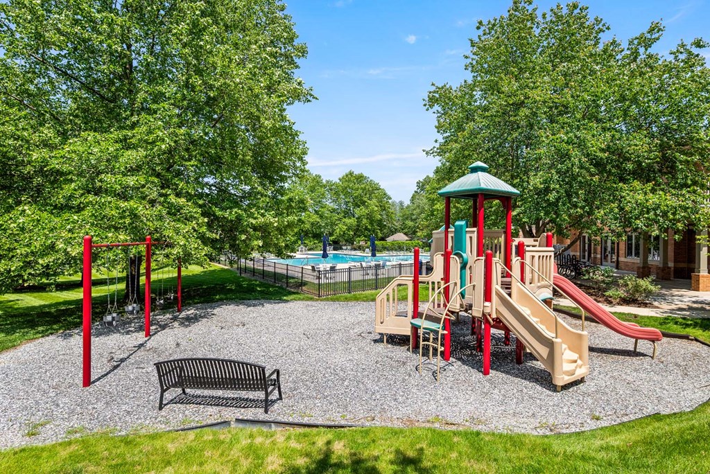 A playground with a slide, swings, and a bench.