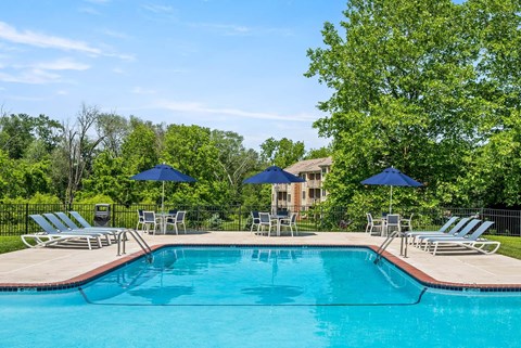 A swimming pool surrounded by lawn chairs and umbrellas.