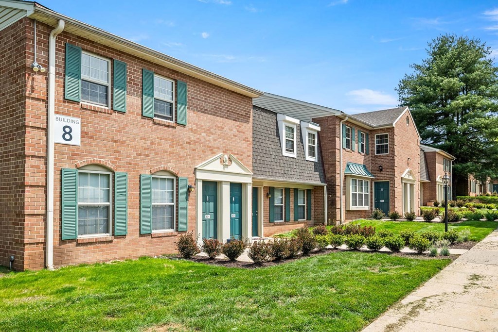 A brick building with green shutters and a white door.
