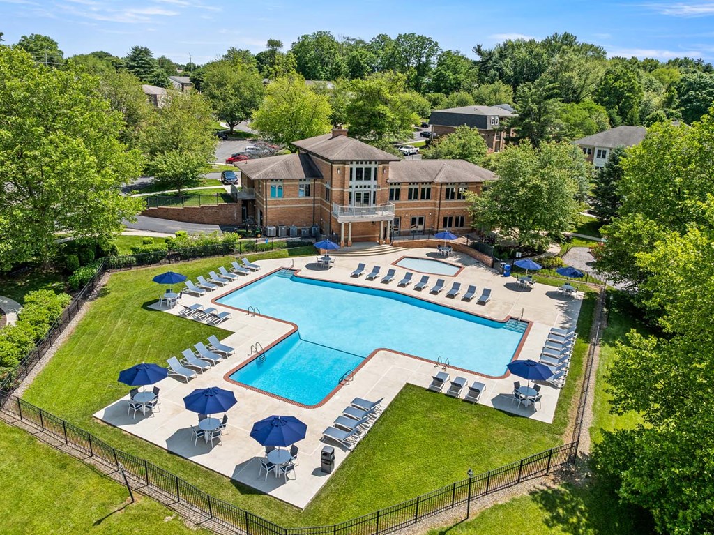 A large swimming pool surrounded by lawn chairs and umbrellas.