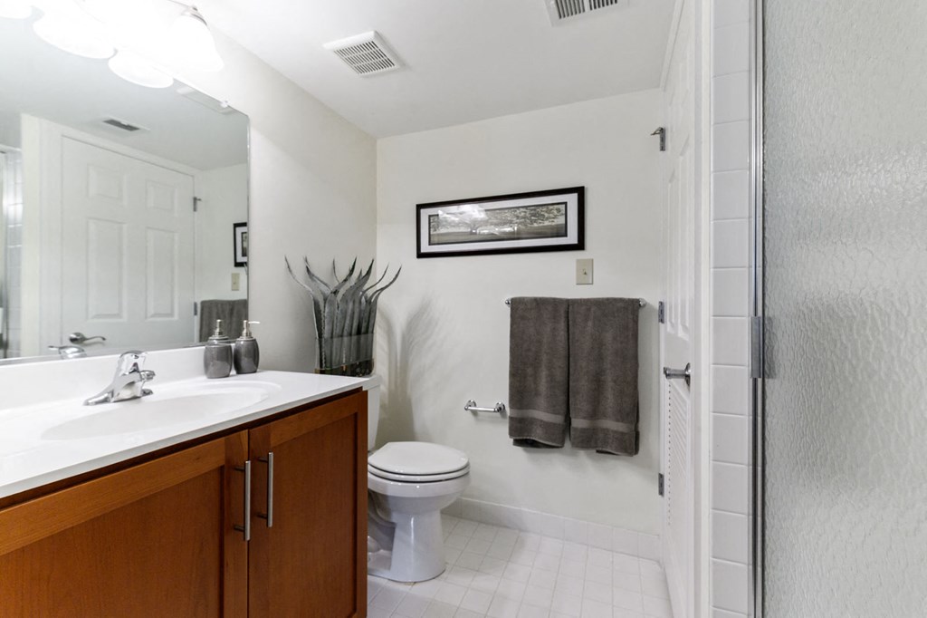 Modern bathroom featuring tile flooring, a spacious vanity with a large sink, a full-length mirror, toilet, and a stand-up shower in the Tahoe apartment at New Kent Apartments, West Chester, PA