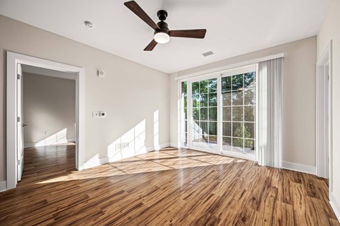 A room with a ceiling fan and a large window.