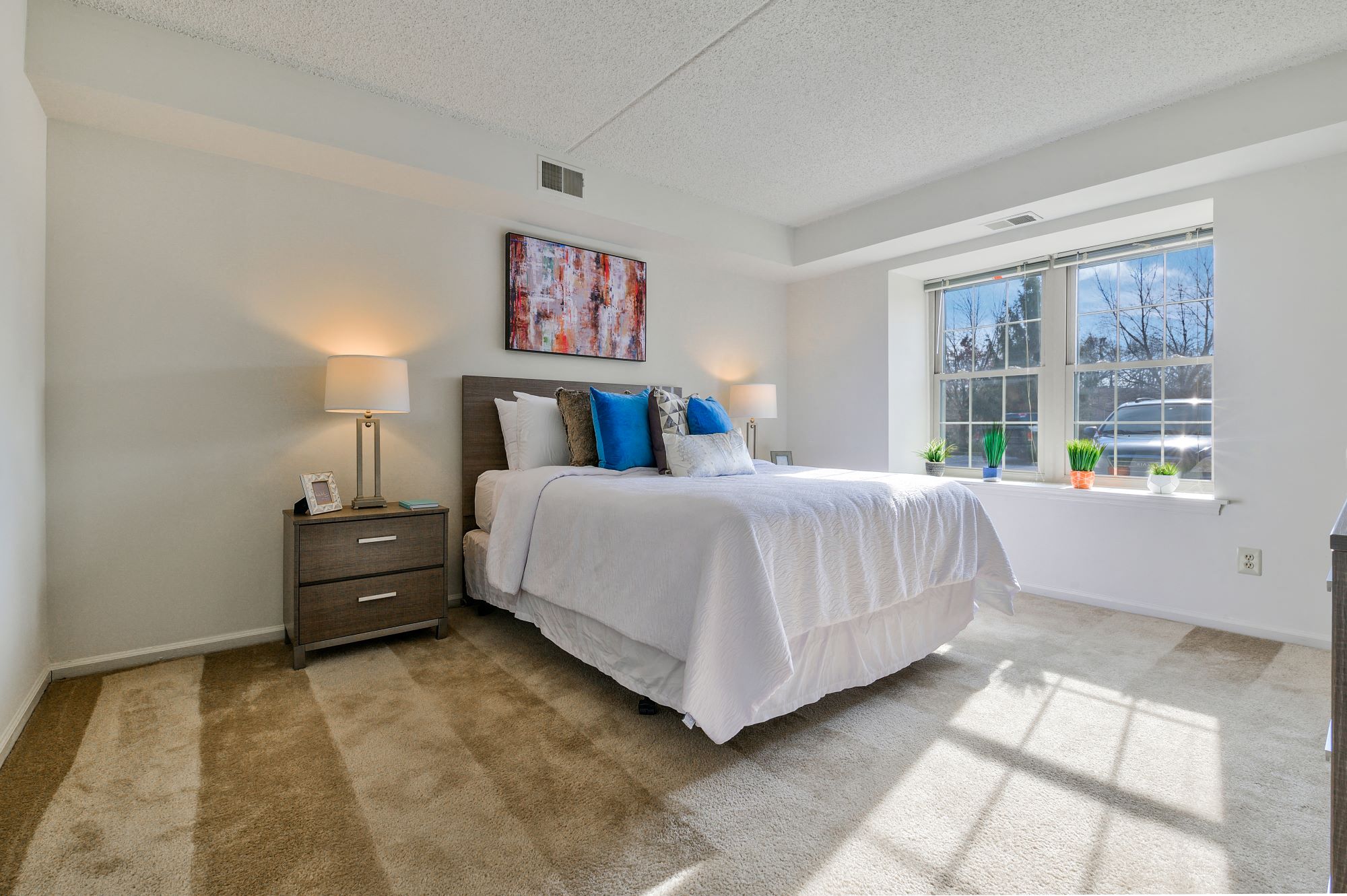 A bedroom with a large bed and a painting on the wall.