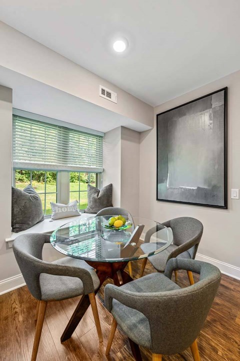 A modern dining room with a glass table and grey chairs.