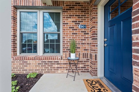 A blue door with a sign on the mat that says "HOME SLUT".