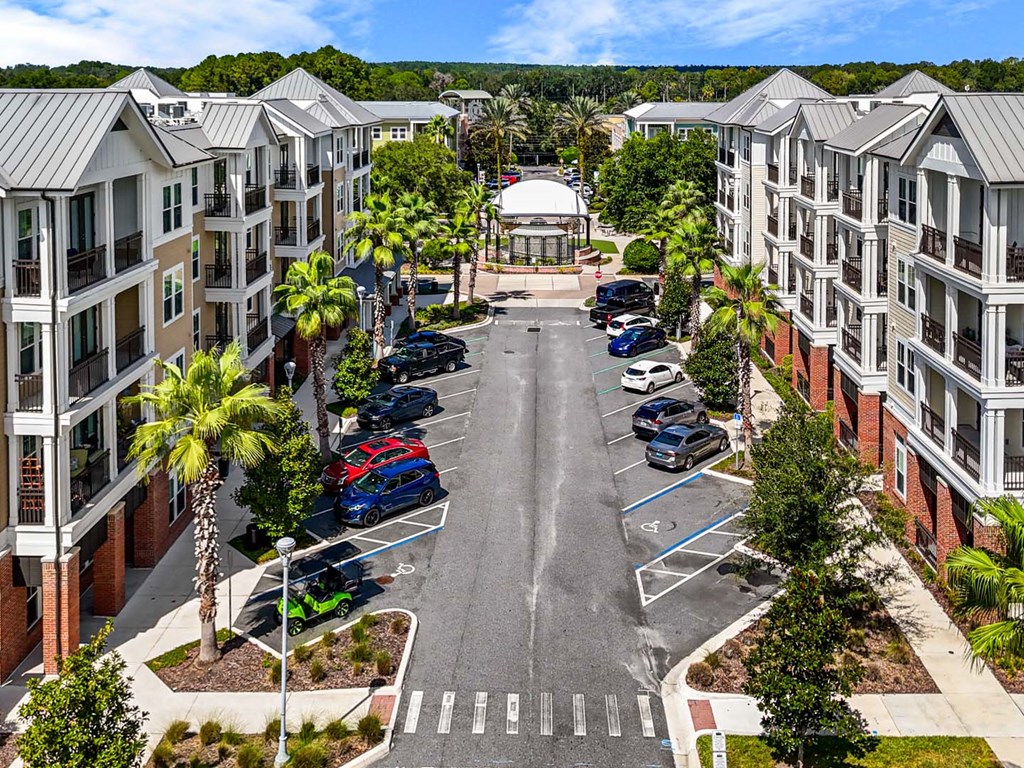A parking lot in front of apartment buildings with cars parked.