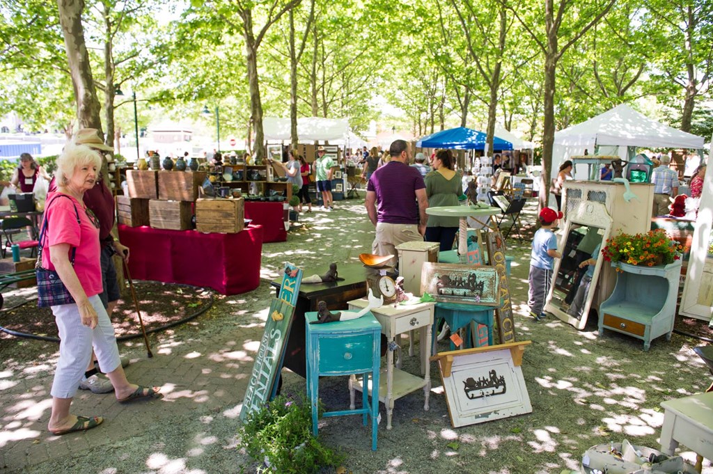 A woman in a pink shirt is walking past a table with a red cloth on it.