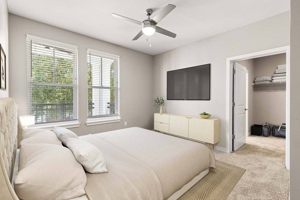 A bedroom with a large bed and a ceiling fan.