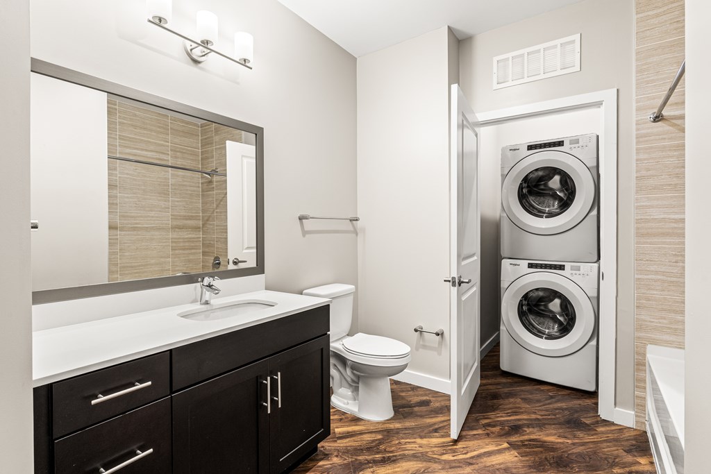 A modern bathroom with a washer and dryer built into the wall.