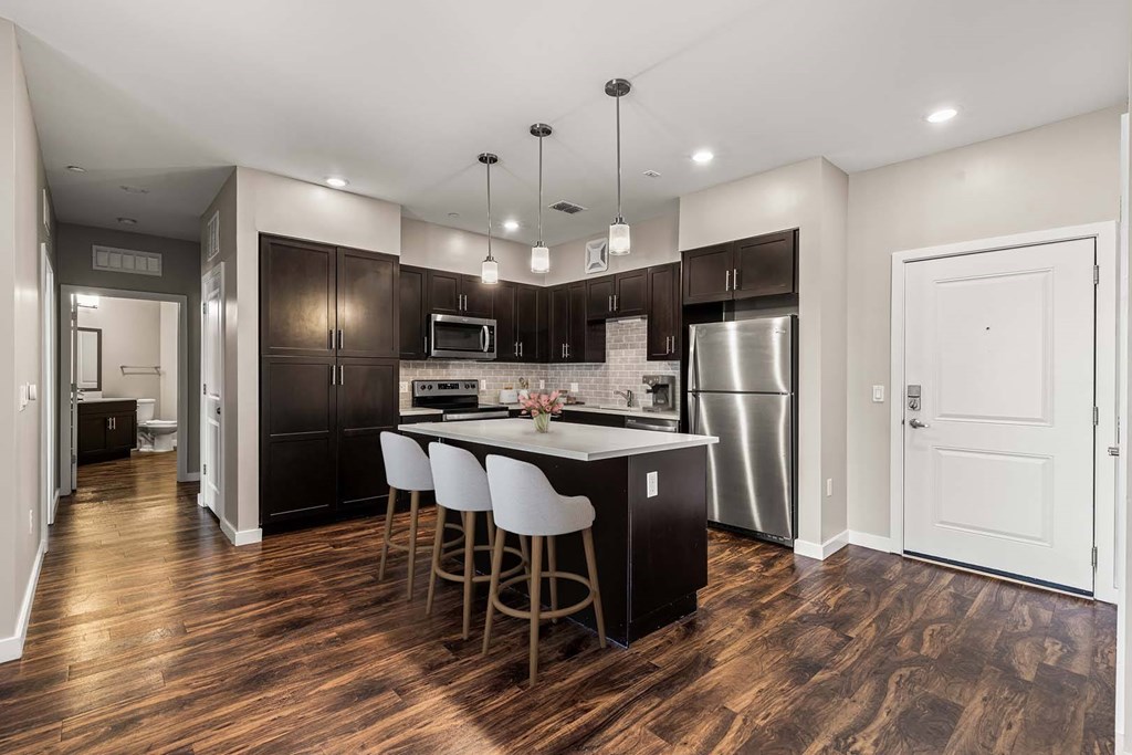 A kitchen with dark wood floors and white walls.