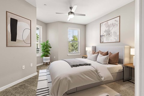 Bedroom at The Flats at Tioga Town Center with bed, bedside lamps, ceiling fan, and plant.