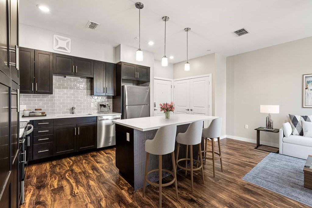 A modern kitchen with dark wood floors and a white island.