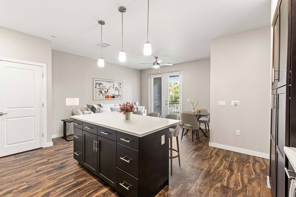 A kitchen with a white island and black cabinets.