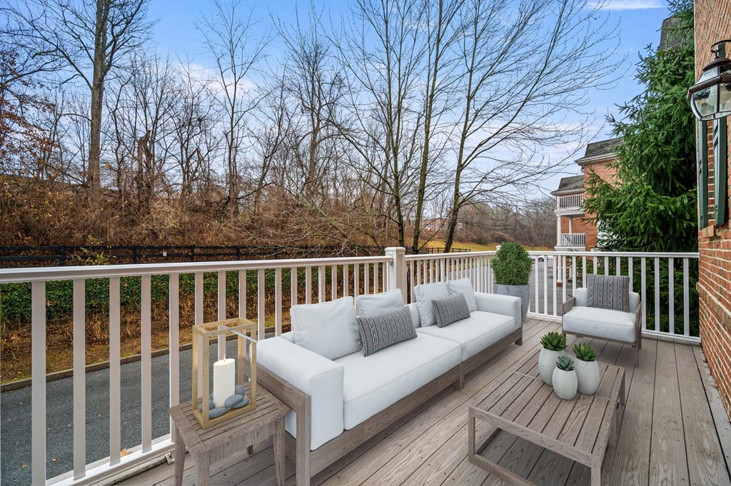 Wooden deck with a white couch and cozy pillows, offering a relaxing outdoor space at Claremont Apartments in Exton, PA