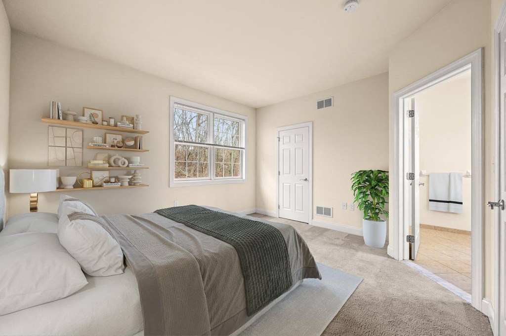 Bright bedroom with a large bed and a window that lets in natural light at Claremont Apartments in Exton, PA