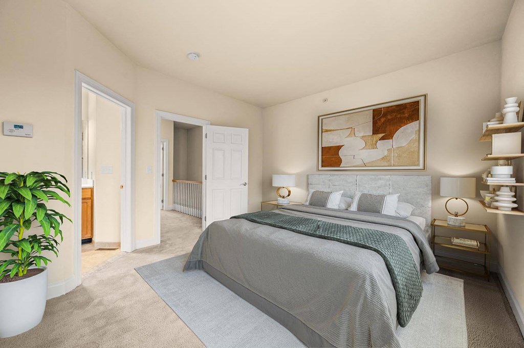 Serene bedroom featuring a large bed and a potted plant, offering a peaceful retreat at Claremont Apartments in Exton, PA