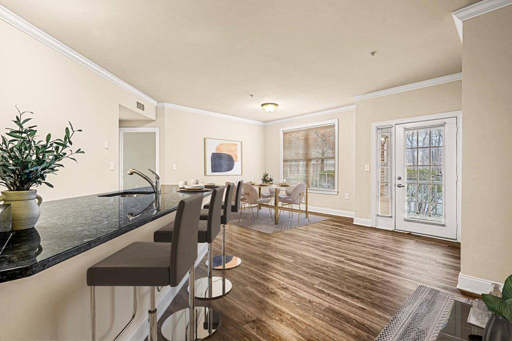 Modern kitchen with sleek black countertops, complemented by a dining area featuring a table and chairs at Claremont Apartments in Exton, PA