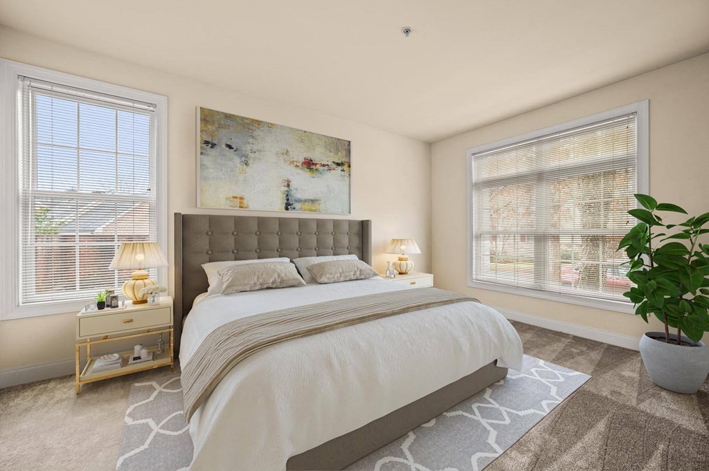 Inviting bedroom with a large bed, a framed painting, and a potted plant, creating a serene atmosphere at Claremont Apartments in Exton, PA