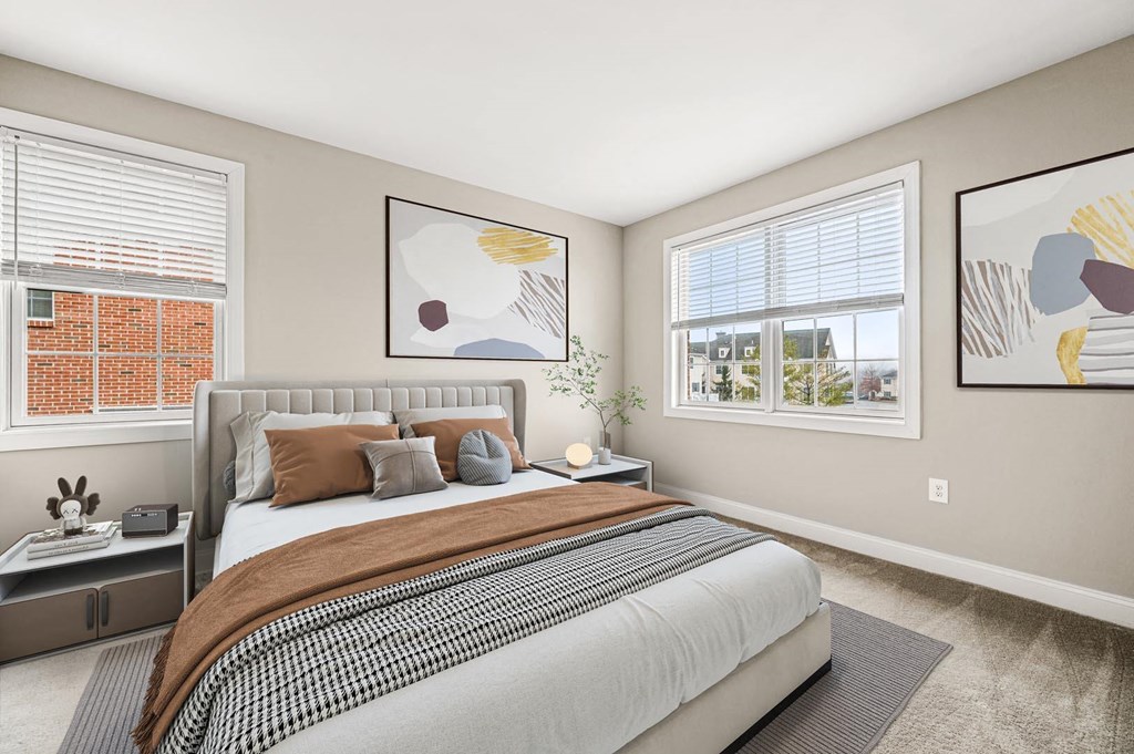 Relaxing bedroom with a large bed and two framed artworks on the wall, adding character to the space at Claremont Apartments in Exton, PA