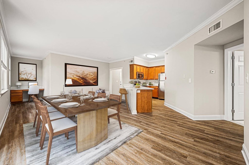 Open concept living space with dining area, wood-inspired floors, granite countertops, and stainless steel appliances at Claremont Apartments in Exton, PA.
