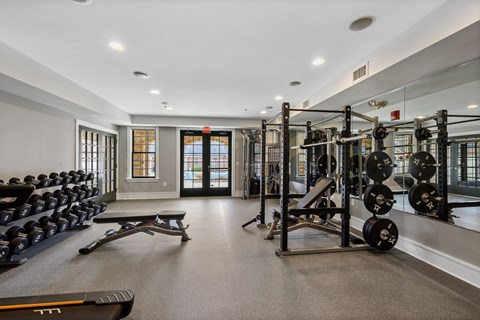 A gym with a variety of equipment including dumbbells, weight plates, and benches.