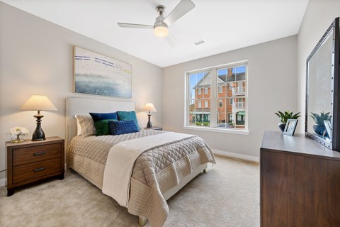 Spacious luxury bedroom with soft natural light and a modern ceiling fan, designed for comfortable living at Claremont on the Square in Exton.