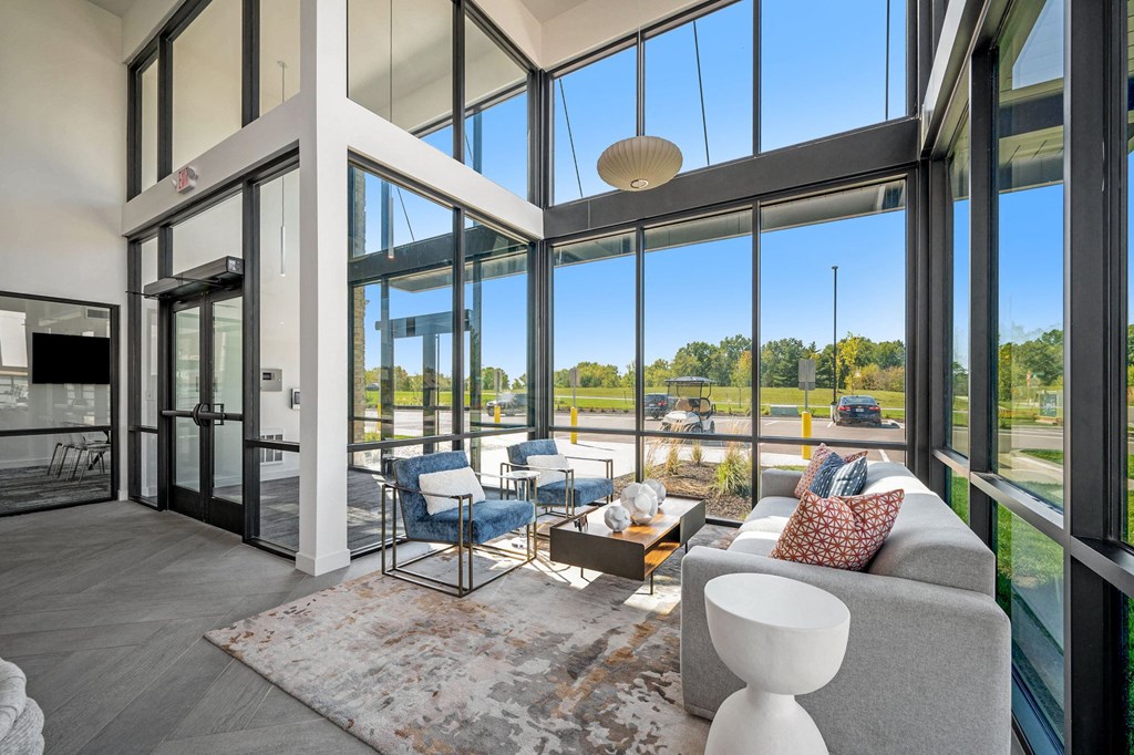 a living room with a couch and chairs and glass doors  at Signature at West Pryor, Lee's Summit