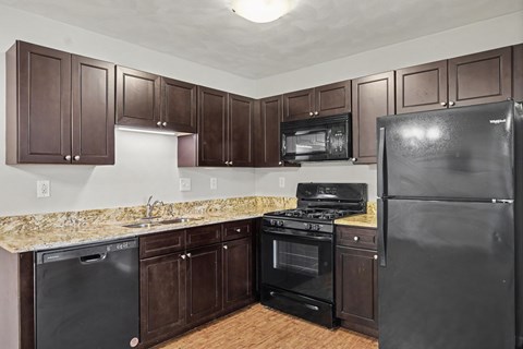 A kitchen with brown cabinets and black appliances.