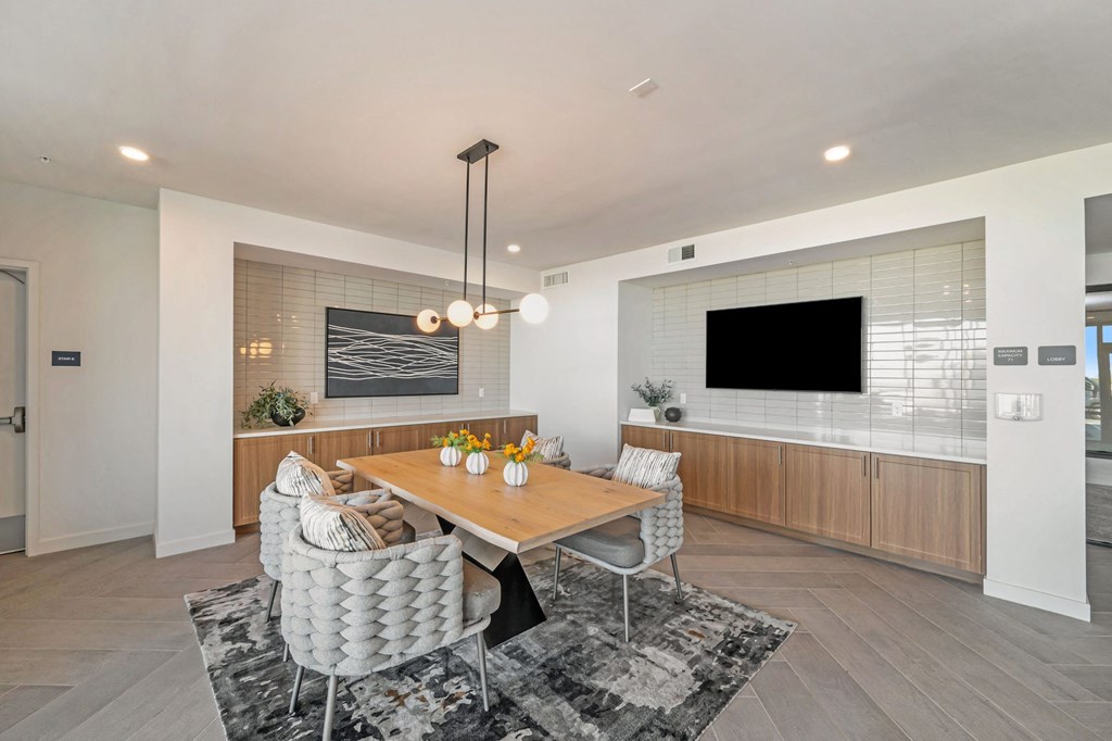 a dining room with a table and chairs and a wall mounted tv a dining room with a table and chairs and a wall mounted tv at Signature at West Pryor, Lee's Summit, Missouri