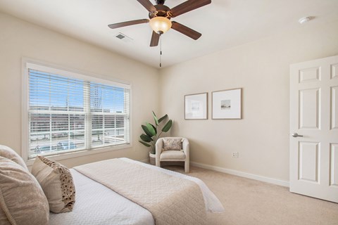 A bedroom with a queen bed, large window, and a 4-speed ceiling fan and dimmable ceiling lights at The Residences at Toscana Park, Granger, IN