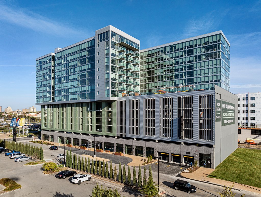 A modern glass and concrete building with cars parked in front. at One Foundry Way Apartments, St Louis, MO