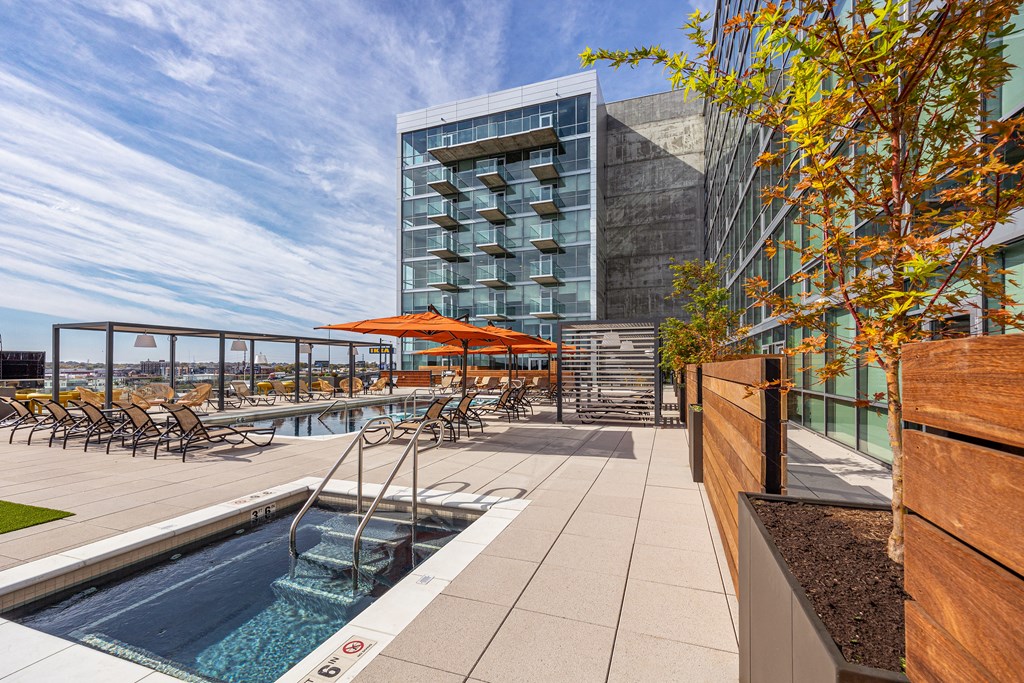 A modern pool area with a glass building in the background. at One Foundry Way Apartments, Missouri, 63110