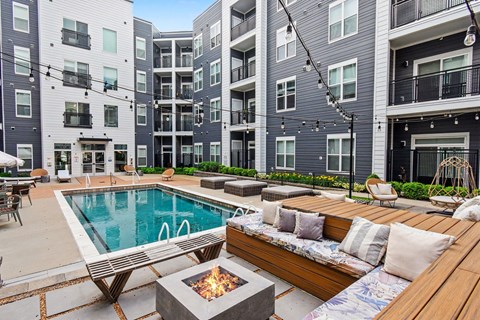 A modern apartment complex with a pool and outdoor seating area.