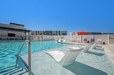 a swimming pool with two chairs and an umbrella in front of a building
