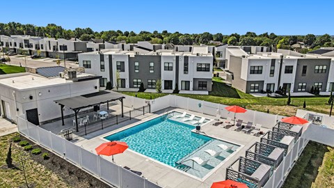 an aerial view of a swimming pool with umbrellas and apartments in the background